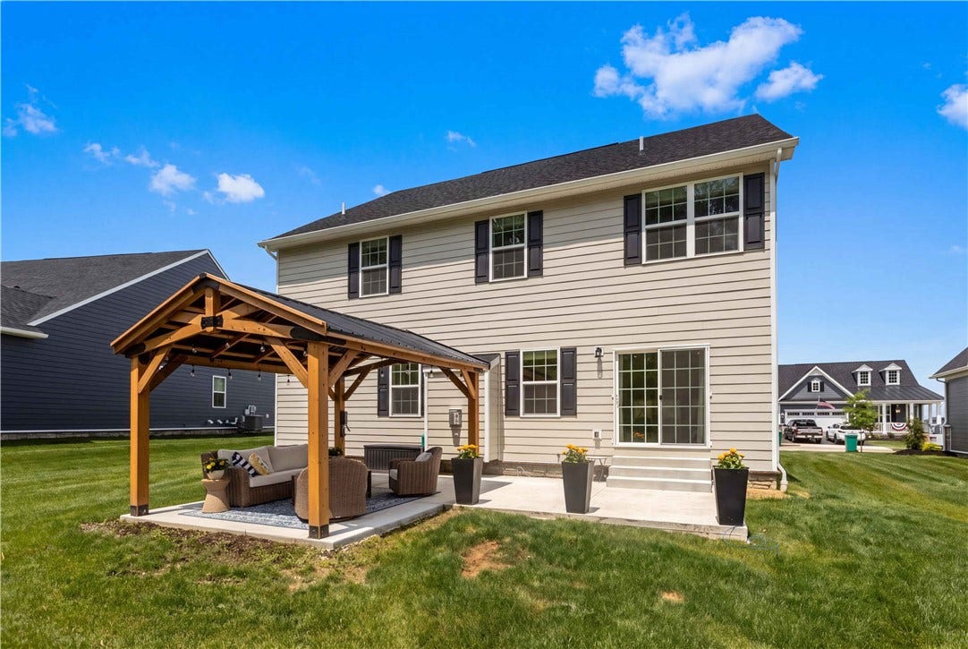 Custom timber-frame pavilion creates an exceptional outdoor living space with soaring exposed beams, a dramatic metal roof, decorative lighting, and expansive concrete patioperfect for relaxing or entertaining in any season.