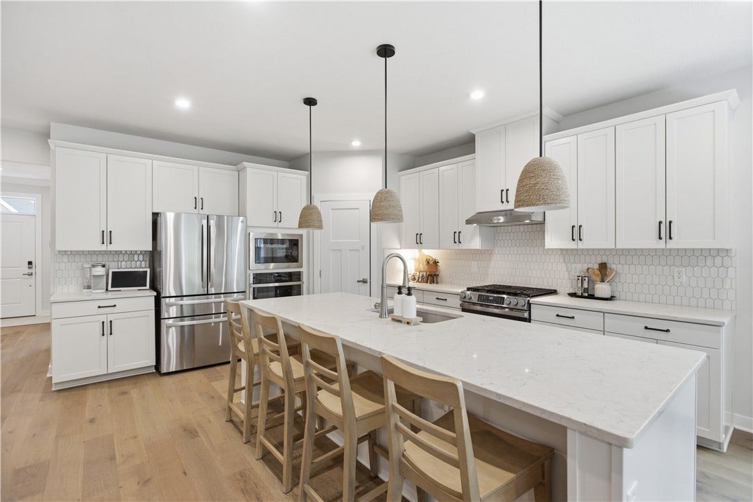 Stunning gourmet kitchen with oversized island, quartz countertops, stainless appliances, and abundant cabinetry.