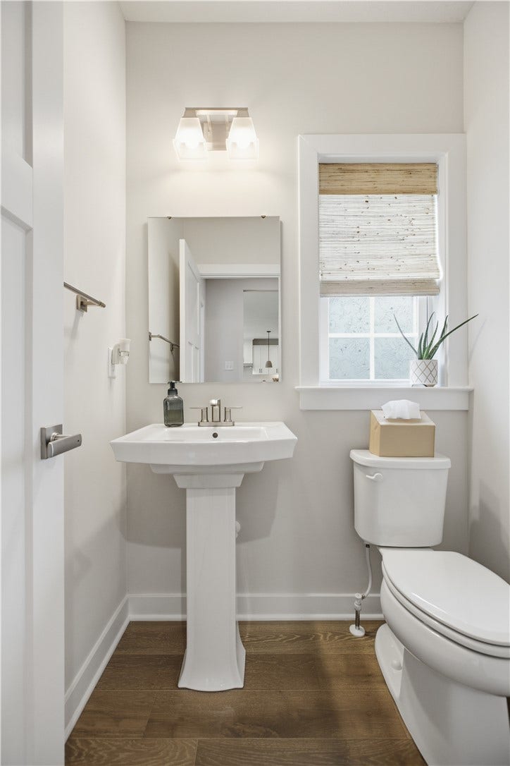 Convenient main-level powder room with pedestal sink, window, and natural light for guests and family.