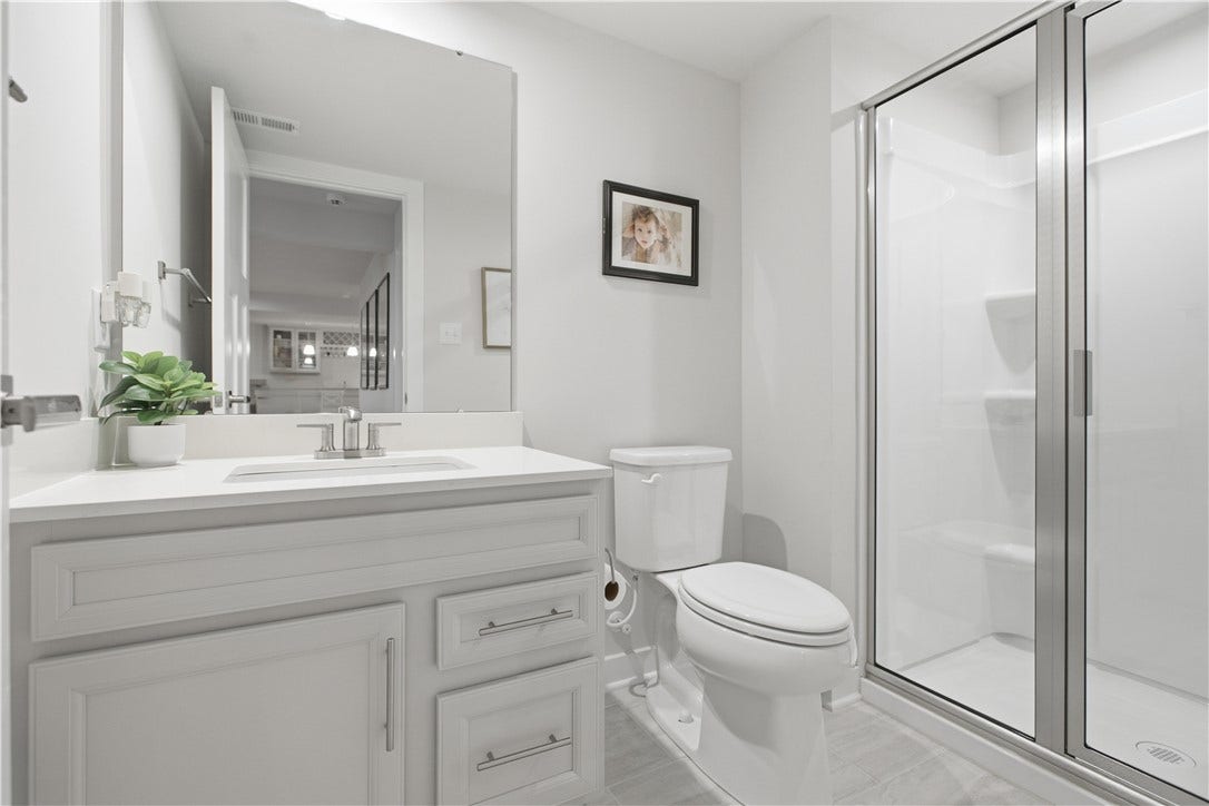 The finished lower level is complemented by a full bath featuring a stylish vanity, premium finishes, durable flooring, and a spacious walk-in showerideal for guests or extended entertaining.