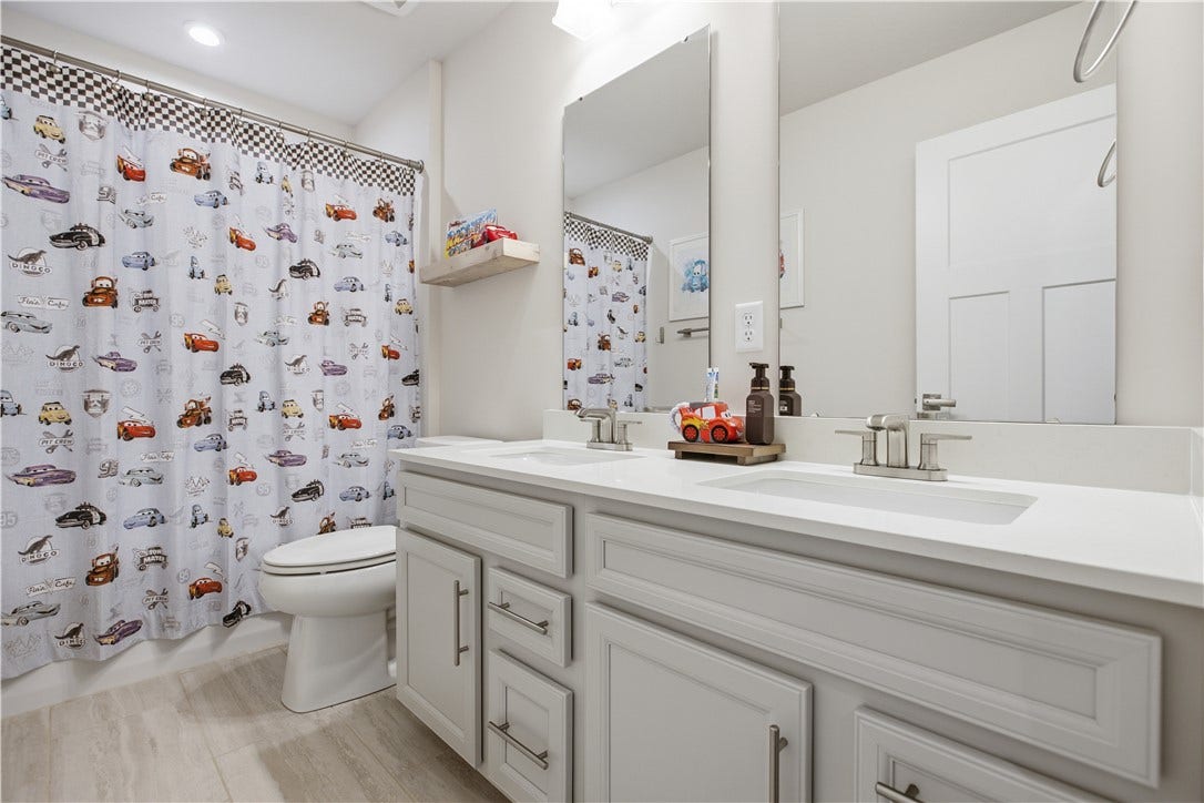 Well-appointed hall bath features oversized dual-sink vanity, abundant storage, and full tub/shower combination.