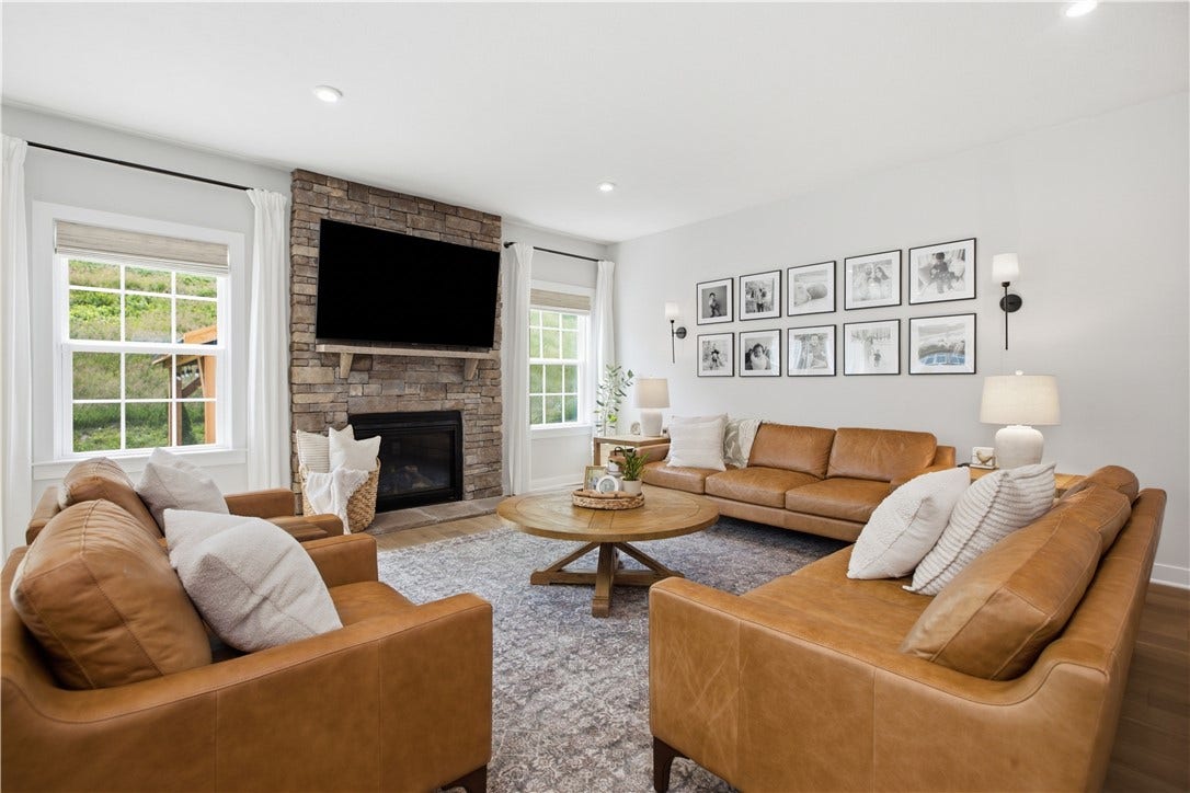 Spacious living room featuring floor-to-ceiling stone fireplace, abundant windows, and recessed lighting throughout.