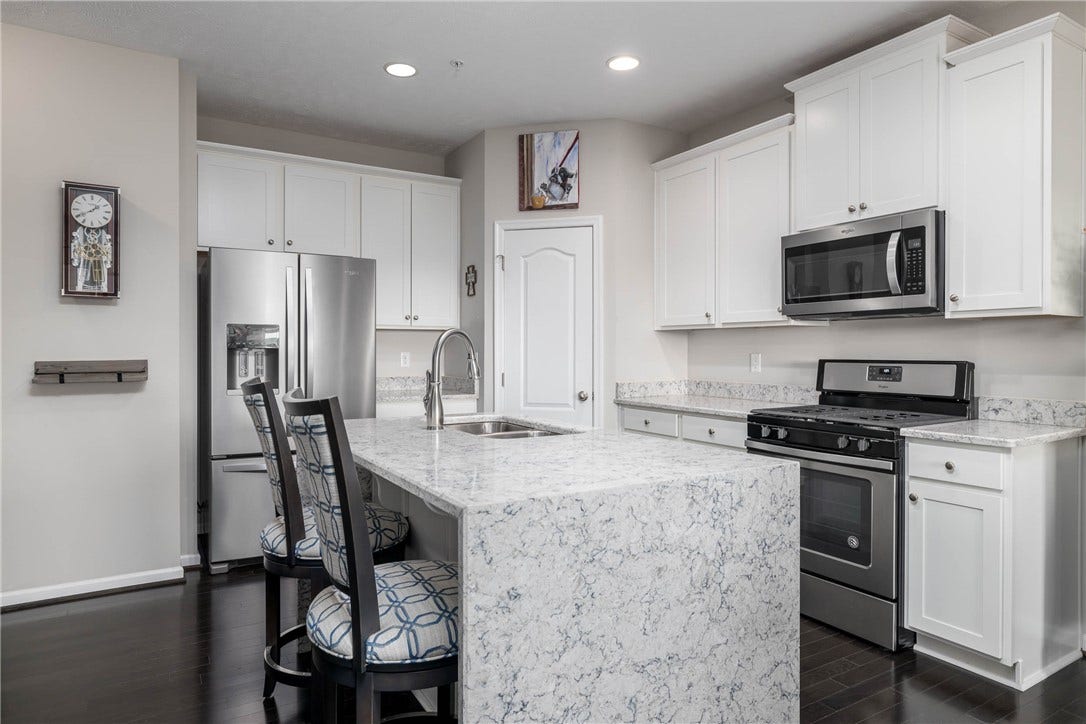 Sleek modern kitchen with quartz countertops, quartz waterfall island.