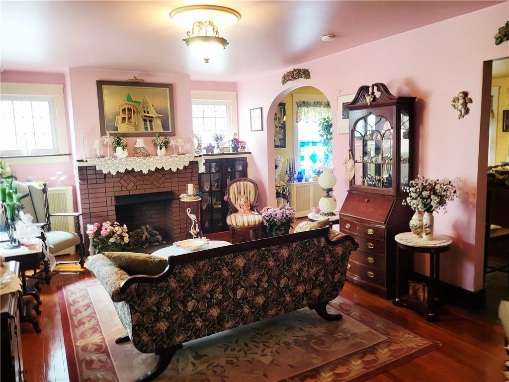 Living room with gleaming hardwood floors and leaded glass windows on either side of gas fireplace