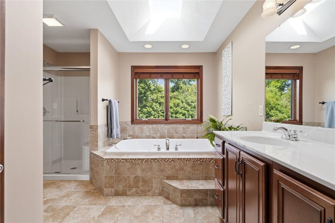 En Suite Primary Bath with Oversized, Tile Surround, Oasis Jetted Tub, Walk in Shower with Glass Door, Double Vanity and Private Toilet.