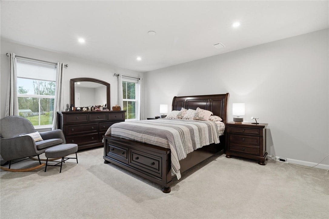 Spacious 16'x13' Primary Bedroom with large picture windows and neutral carpeting and paint.