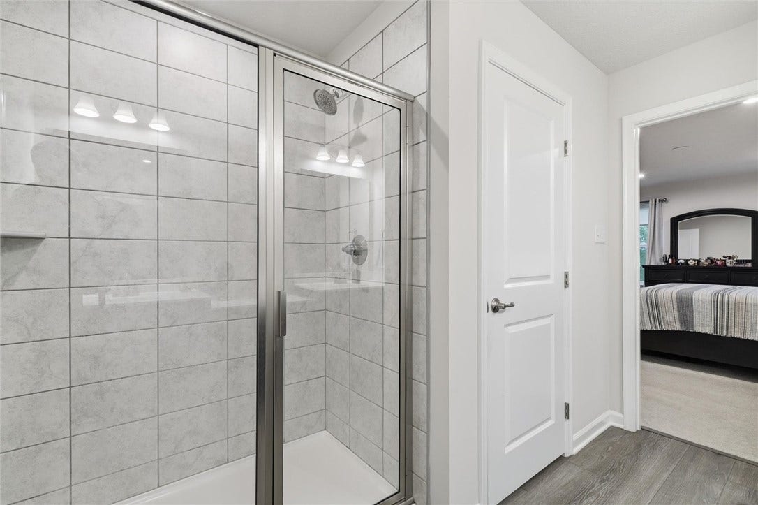 A full-tile shower with rainhead faucet and sleek glass doors completes the primary bath.