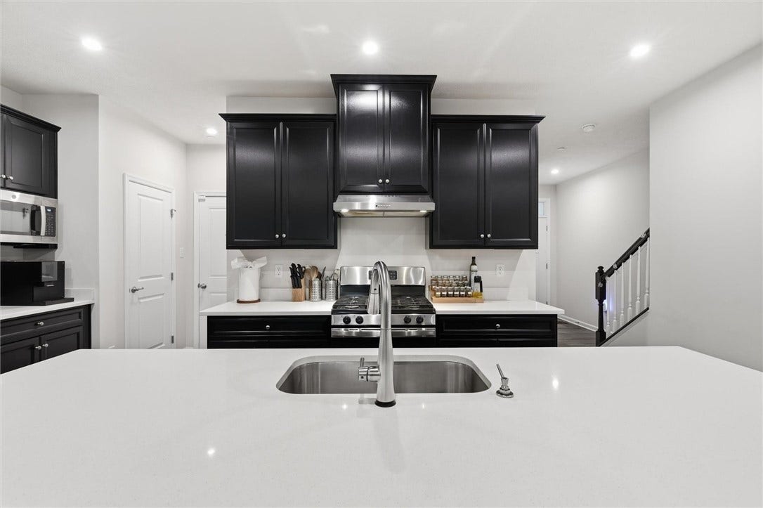 Sophisticated black cabinetry with 42" raised-panel uppers and crown molding, paired with sleek white quartz counters for a crisp, contemporary finish.