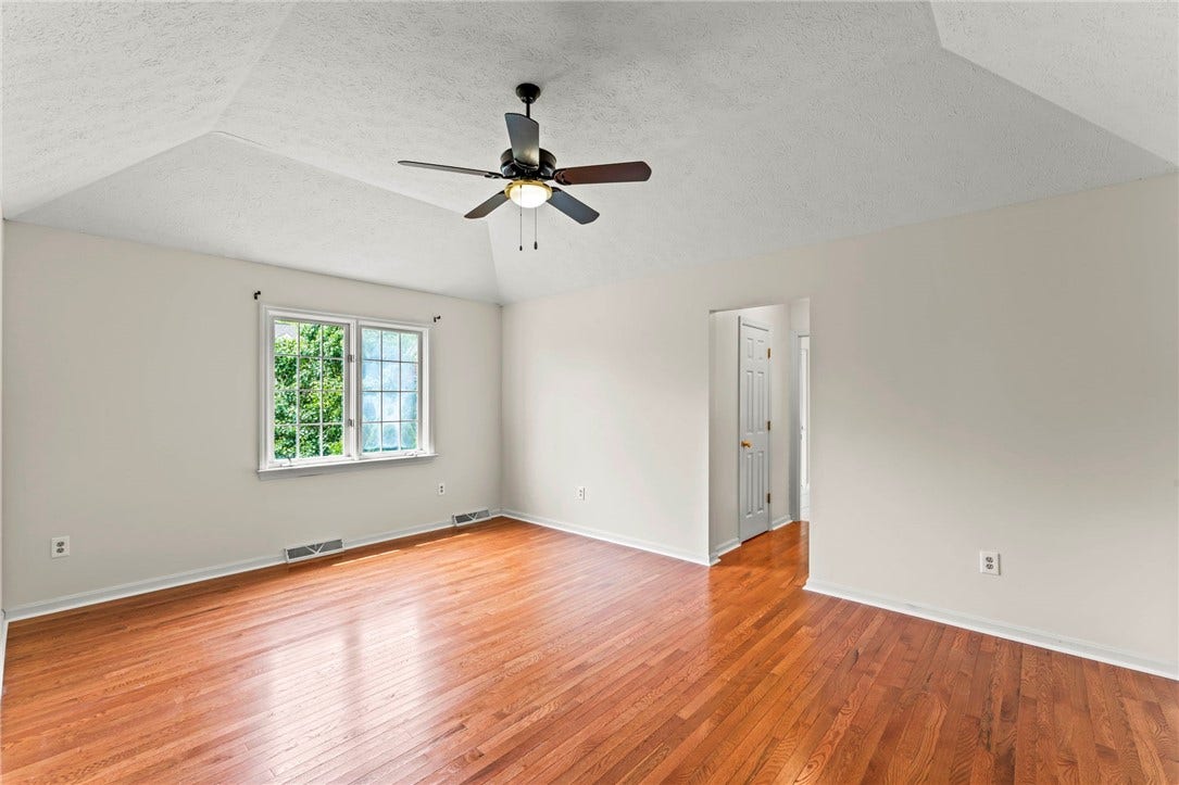The impressive primary bedroom is designed for comfort and relaxation and features a tray ceiling, beautiful hardwood flooring, and two generous walk-in closets.