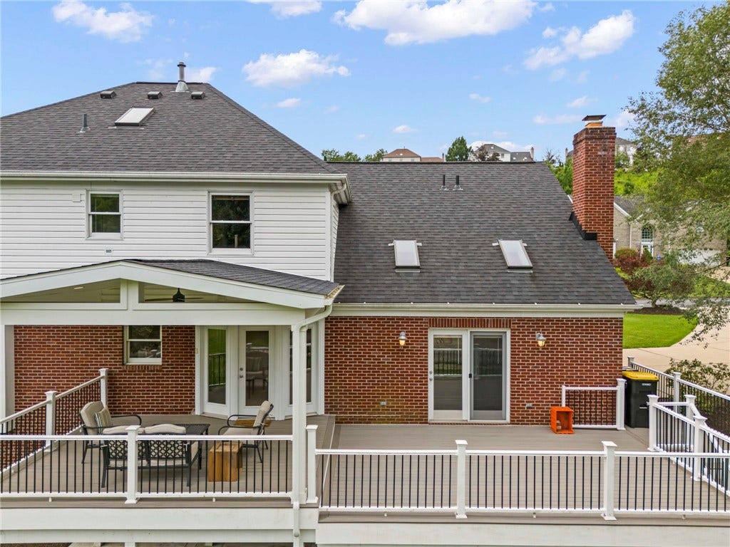 impressive approximately 14' x 18' composite covered deck featuring a soaring cathedral ceiling. Whether you're hosting summer barbecues, enjoying your morning coffee, or relaxing after a long day, this outdoor living space is designed to be enjoyed in every season. Steps provide convenient access to both the backyard and driveway.
