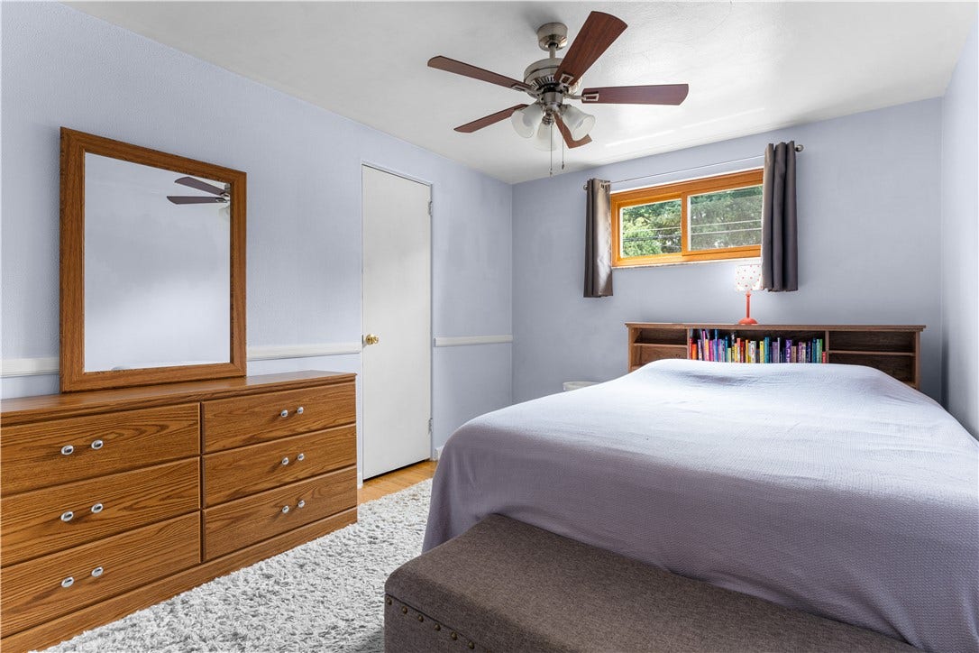 The second bedroom is appointed with hardwood flooring, a ceiling fan, and decorative chair rail molding.