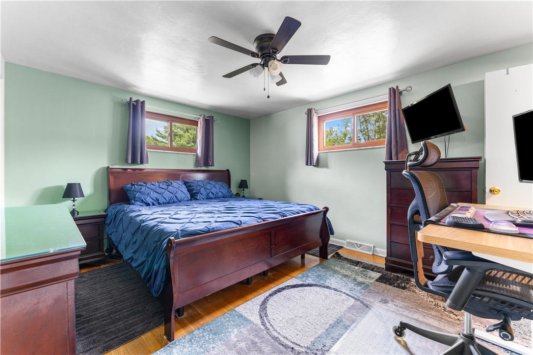 The primary bedroom offers a tranquil retreat, complete with hardwood flooring, a ceiling fan, and an en suite bathroom.