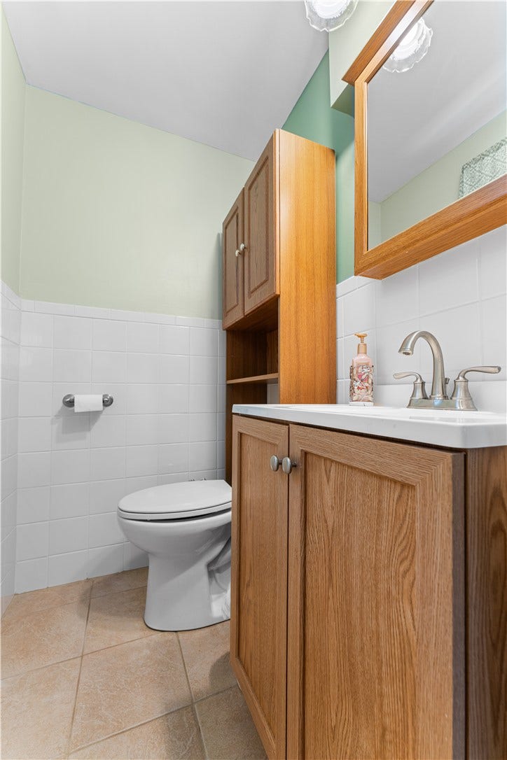 Ceramic tile flooring, half-wall tile surround, and abundant natural light.