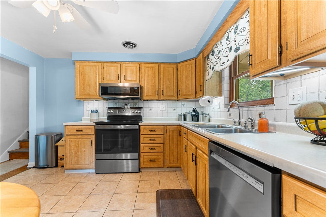 This kitchen features oak-look cabinetry, ceramic tile flooring, and stainless steel appliances, making it an ideal space for the family chef.