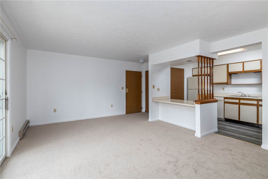 Living room with view to kitchen and entrance door.