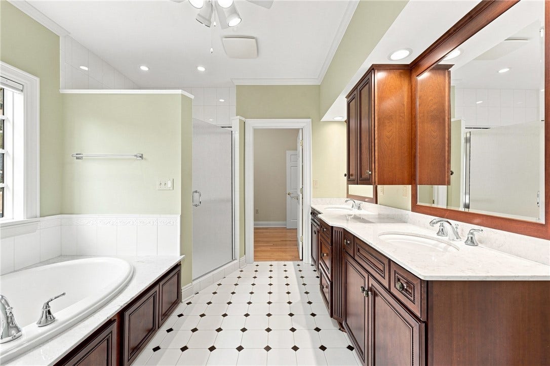 Featuring a deep soaking tub, a separate shower, a double vanity and custom cabinetry, the ensuite bath is one any couple can share.