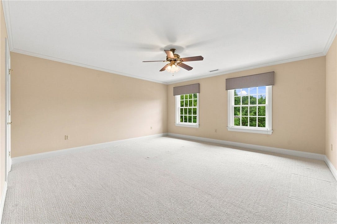 The fifth bedroom is warmly lit by two large windows, making the space soothingly bright.