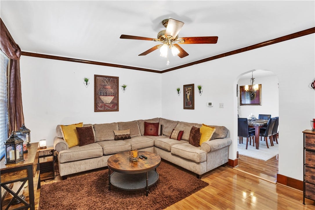 804  Spacious living room with crown molding, shiny laminate flooring, ceiling fan. Notice the character & charm of the arch way