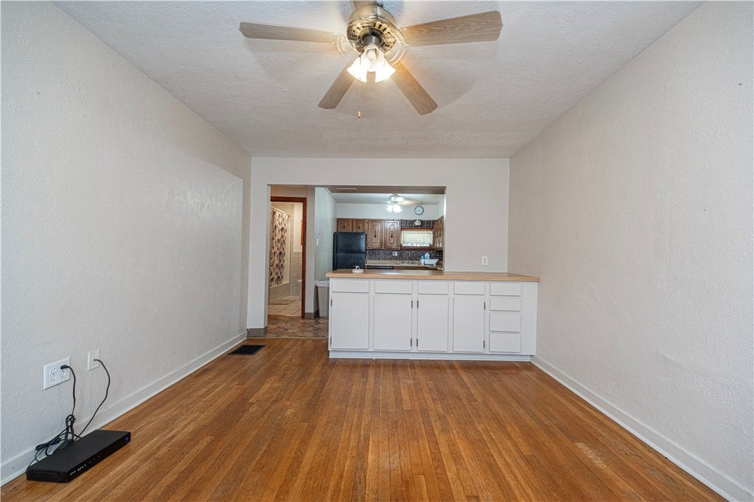 The dining room has great hardwood floors, a spacious cabinet, and a ceiling fan.