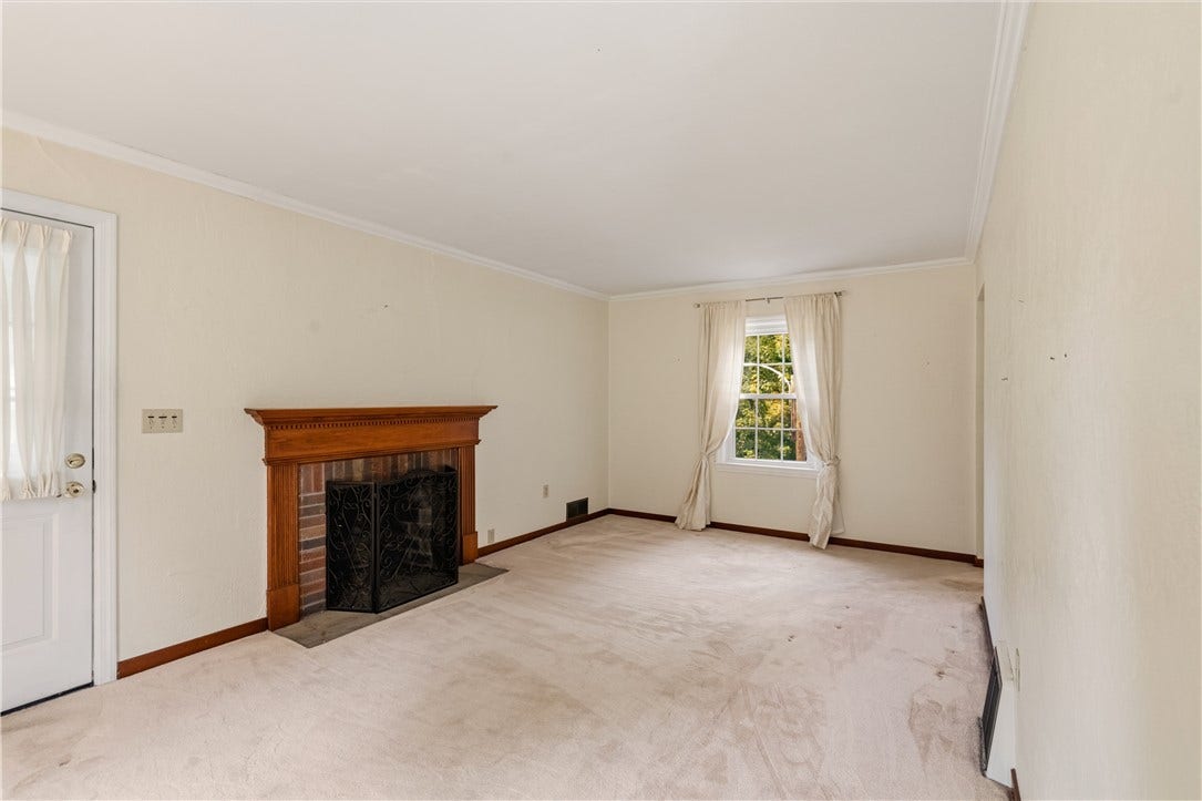 Gas fireplace, crown molding and door leading to 3 season porch. There is hardwood flooring underneath the carpet.