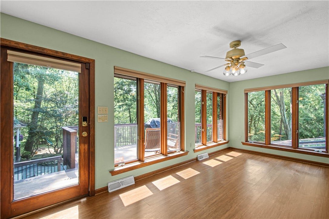Surrounded by windows and wooded views, the sunroom offers a peaceful place for morning coffee, reading, or enjoying the seasons.