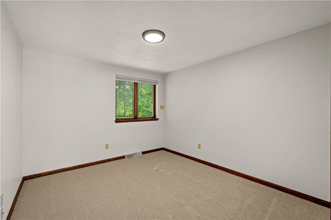 Comfortable third bedroom with natural light and a peaceful view of the surrounding greenery.