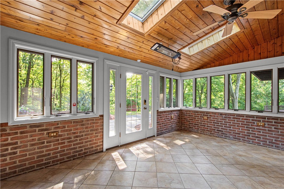 Warm wood ceilings, exposed brick, skylights, and walls of windows create an inviting indoor-outdoor retreat.