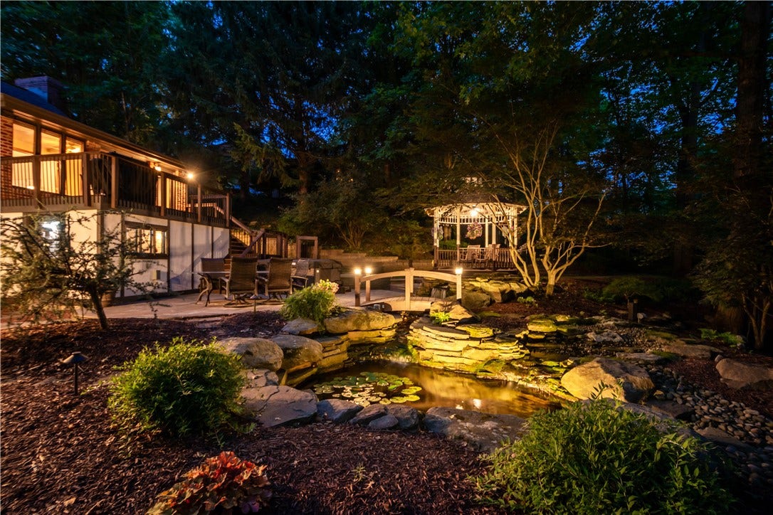 Landscape lighting, the koi pond, waterfall, and gazebo transform the backyard into a magical evening retreat.
