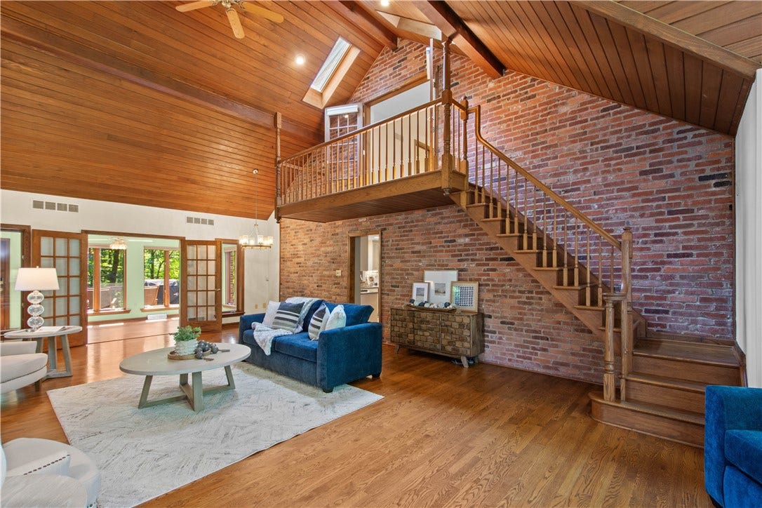 A dramatic brick wall and second staircase showcase the distinctive character that sets this home apart.
