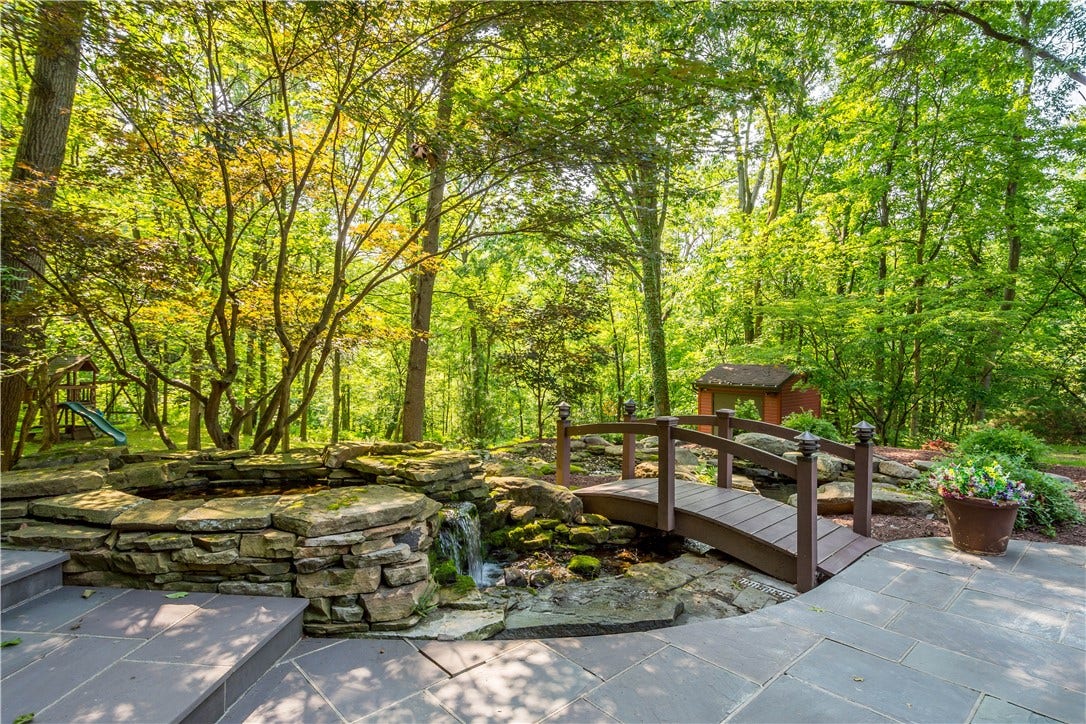 A tranquil koi pond, waterfall, natural stonework, and wooded surroundings create a peaceful escape just steps from home.