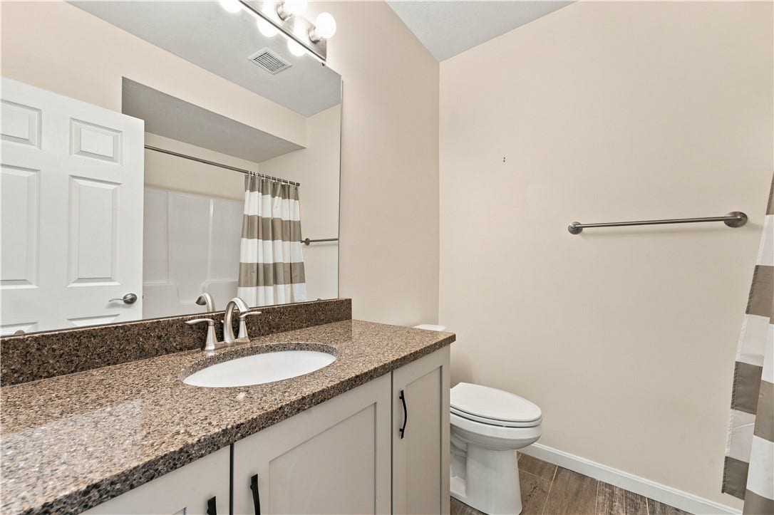 Full Bath Features a Stone Topped Vanity and a Tub/Shower Unit