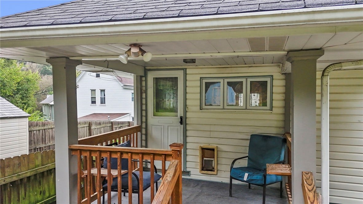 Front covered porch with a fenced in front lawn.
