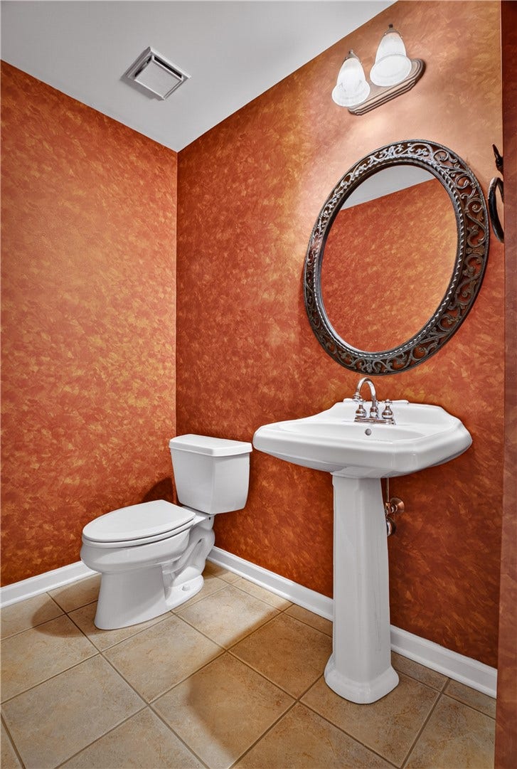 MAIN LEVEL POWDER ROOM WITH PEDESTAL SINK AND TILE FLOORING.