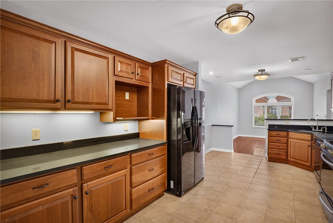 SPACIOUS KITCHEN FEATURING WARM WOOD CABINETRY AND TILE FLOORING.