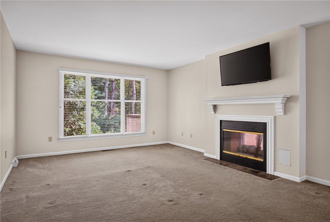 SPACIOUS MAIN LEVEL PRIMARY BEDROOM WITH A FIREPLACE AND WOODED VIEW.