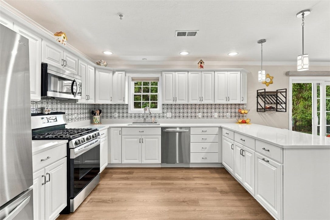 Gas range, stainless steel appliances, updated backsplash and crisp white solid-surface countertops give the kitchen a fresh, modern feel.