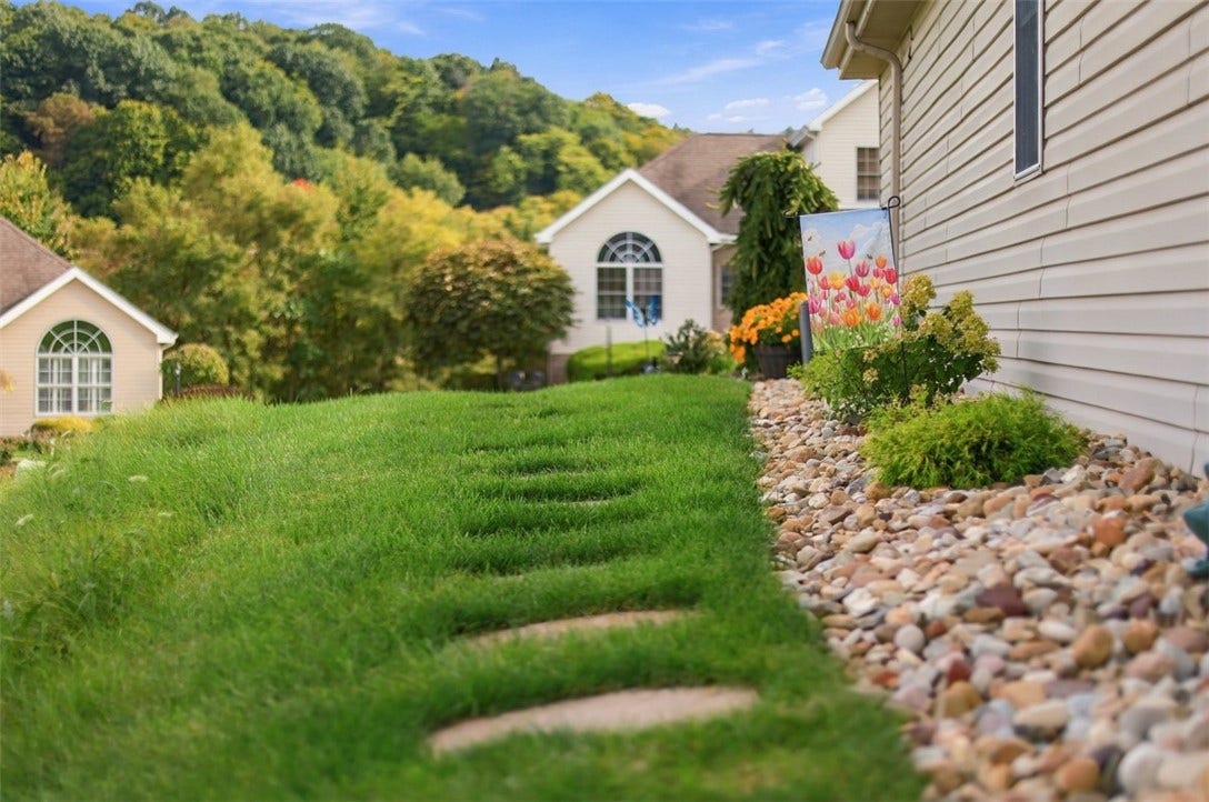 Professionally landscaped grounds feature stepping stones, thoughtfully selected plantings for seasonal color and decorative stone for proper drainage.