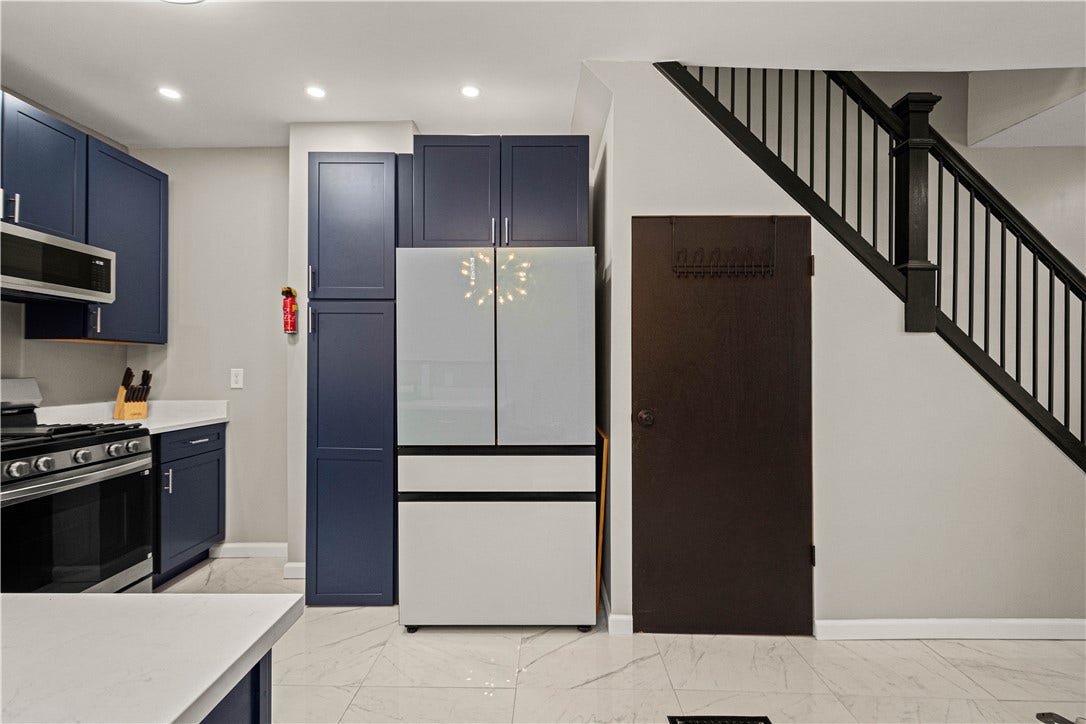214 N Aiken Ave, Pittsburgh, PA 15206 Kitchen with navy cabinetry and refrigerator; stairs to second floor