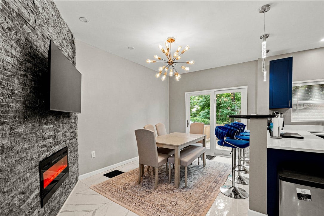 214 N Aiken Ave, Pittsburgh, PA 15206 Dining area with statement chandelier, electric fireplace and sliders to the deck