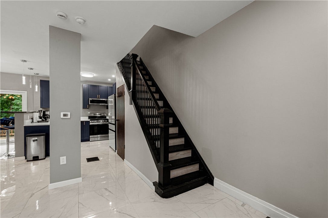 214 N Aiken Ave, Pittsburgh, PA 15206 Open staircase with black railing; marble-look tile throughout the main level