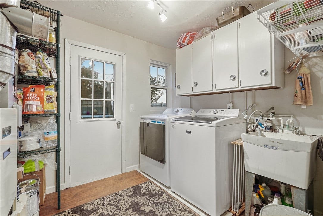First floor laundry room with storage cabinets, laundry sink and door to backyard.