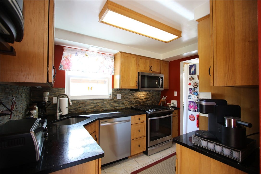 4239 Finleyville Elrama Road, Finleyville, PA 15332 Beautifully Updated Kitchen accented by Stacked Stone Backsplash, Plenty of Wood Cabinets, Quartz Counter Tops, Ceramic Tiled Floors & Stainless-Steel Gas Stove, Microwave, Newer Dishwasher & Refrigerator offering in door water & ice dispenser