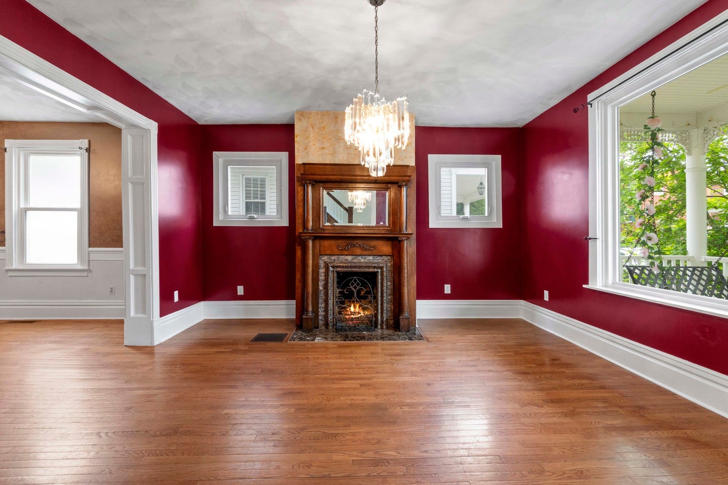 The living room is enhanced by beautiful wood floors, an antique fireplace and mantle, a large picture window, chunky painted baseboards and a bold color pallete.