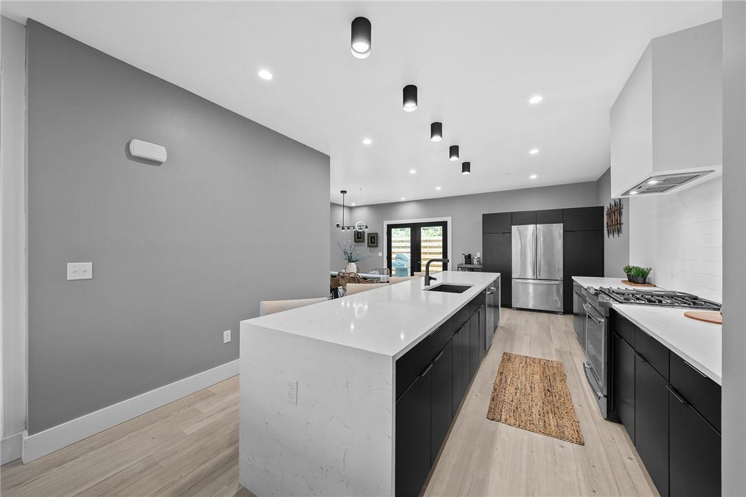 240 E Jefferson, Pittsburgh, PA 15212 Stunning contemporary kitchen featuring an oversized Carrara quartz waterfall island with generous seating, sleek custom Wolf cabinetry, premium JennAir stainless steel appliances, and a stylish tile backsplash. Modern lighting and clean architectural lines complete the space, which opens seamlessly to the living and dining areasperfect for everyday living and entertaining.