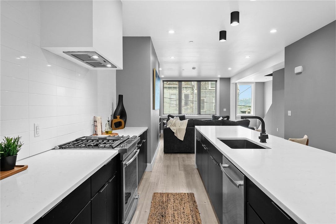 240 E Jefferson, Pittsburgh, PA 15212 Stunning contemporary kitchen featuring an oversized Carrara quartz waterfall island with generous seating, sleek custom Wolf cabinetry, premium JennAir stainless steel appliances, and a stylish tile backsplash. Modern lighting and clean architectural lines complete the space, which opens seamlessly to the living and dining areasperfect for everyday living and entertaining.