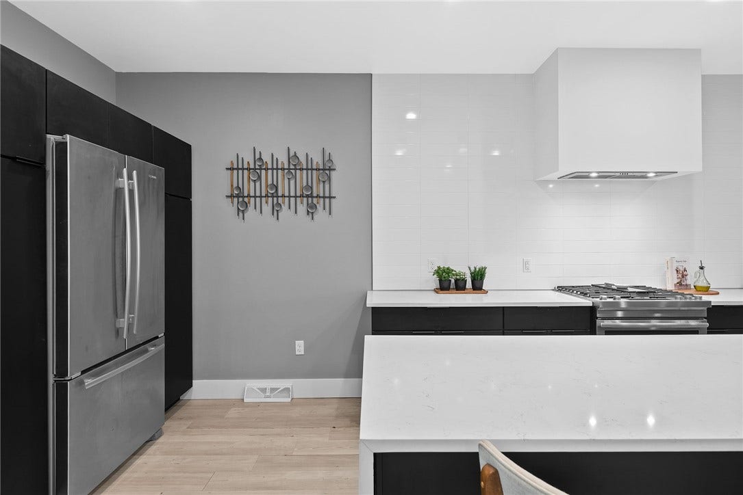 240 E Jefferson, Pittsburgh, PA 15212 Stunning contemporary kitchen featuring an oversized Carrara quartz waterfall island with generous seating, sleek custom Wolf cabinetry, premium JennAir stainless steel appliances, and a stylish tile backsplash. Modern lighting and clean architectural lines complete the space, which opens seamlessly to the living and dining areasperfect for everyday living and entertaining.